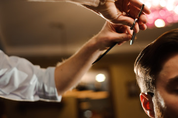 Master cuts hair and beard of men in the barbershop