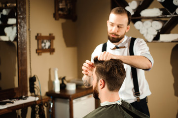 Fototapeta premium Master cuts hair and beard of men in the barbershop