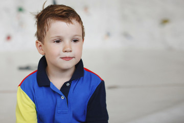 Cute little boy sitting deep in thought at the wall climbing