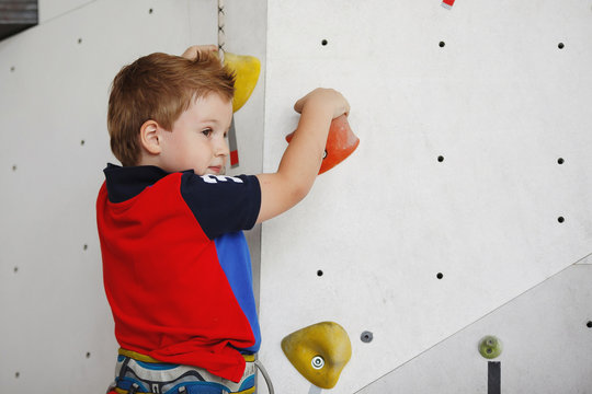 Cute little boy sitting deep in thought at the wall climbing