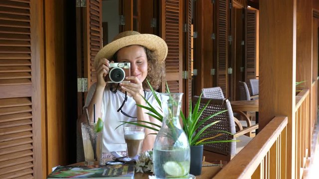 Tourist Woman In Hat Taking Retro Photograph In Cafe With Coffee. Slow Motion. 4K. 