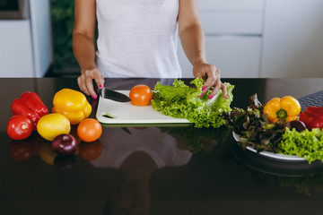 A young woman cuts vegetables in the kitchen with a knife. Healthy food - Vegetable salad. Diet. Dieting concept. Healthy lifestyle. Cooking at home. Prepare food. Close up