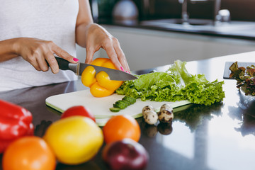 A young woman cuts vegetables in the kitchen with a knife. Healthy food - Vegetable salad. Diet. Dieting concept. Healthy lifestyle. Cooking at home. Prepare food. Close up