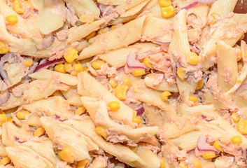 Cooked pasta with red onion, tuna and corn, transparent plate isolated, close up