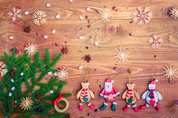 Christmas background with straw decorations, spices, marshmallow on old rustic wooden board, top view, copy space