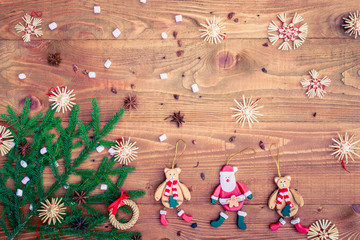 Christmas background with straw decorations, spices, marshmallow on old rustic wooden board, top view, copy space