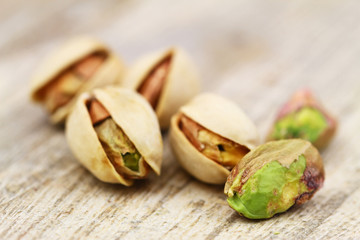 Close up of few pistachio nuts on rustic wooden surface

