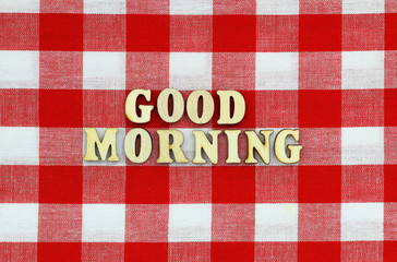 Good morning written with wooden letters on red and white checkered cloth
