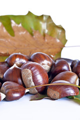 frutta autunnale, castagne e uva  composizione con castagne ed uva, foglie appassite, sfondo bianco