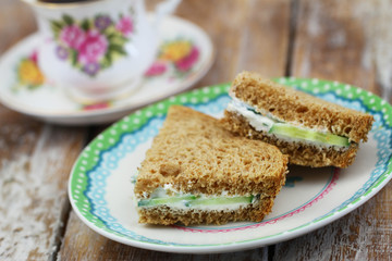 Brown bread sandwiches with cream cheese on plate with cup of tea in vintage cup
