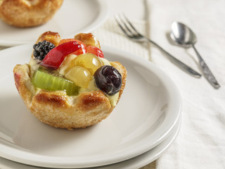 Squisito tortino di pasta sfoglia alla furtta e crema su piatto bianco