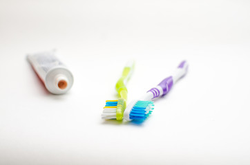 On a white background lies toothpaste and two brushes