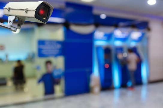 CCTV security indoor camera system operating with blurred image of people queuing to withdraw money from ATM (Automated Teller Machine), finance, surveillance security and safety technology concept