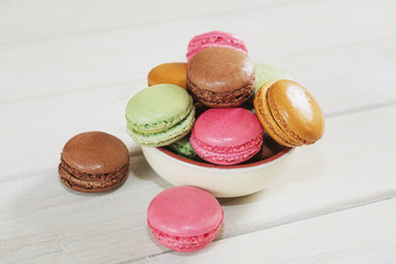 Bowl filled with macaroons with the flavors of coffee, pistachio, chocolate and raspberries.