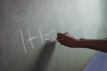 Cropped hand of student writing on blackboard