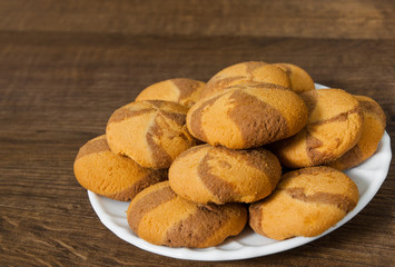 Cookies on the white plate on a wooden background