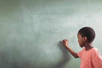 Schoolboy writing on chalkboard - Powered by Adobe