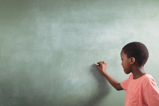 Schoolboy Writing On Chalkboard