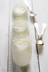 Homemade yogurt in a glass jar on a wooden table. Rustic style, selective focus.