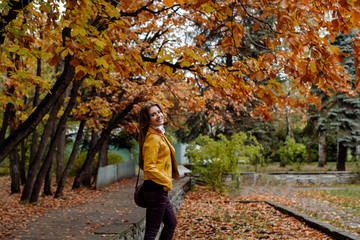 autumn portrait of a beautiful smile girl with long fair-haired hair in yellow leather jacket 