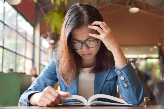 Stressed Woman in Blue shirt reading a book.