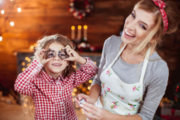 Obraz premium Merry Christmas and Happy Holidays. Family preparation holiday food. Mother and daughter cooking cookies in New Year interior with Christmas tree.
