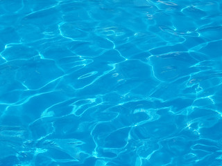 Fototapeta na wymiar rippled that reflect sunlight on blue water surface in resort swimming pool