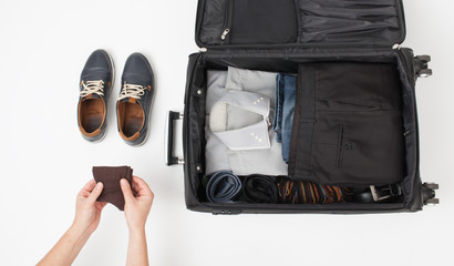 Male hand put things in suitcase on white