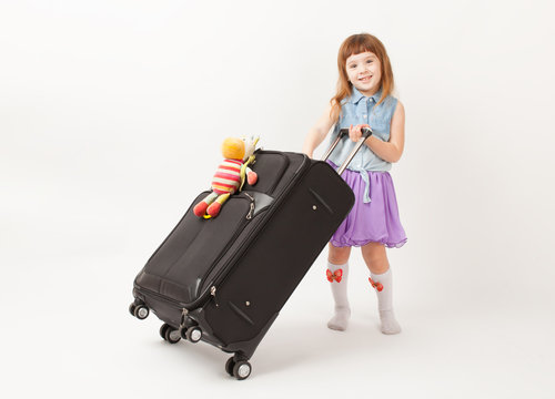 Girl standing with travel suitcase and smiling