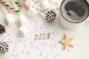 Homemade Christmas cookies, number year 2018, desserts, stars decor, candy cane, marshmallow, cup of coffee on a white background.