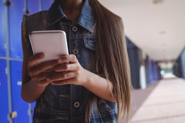 Elementary student using smartphone in corridor