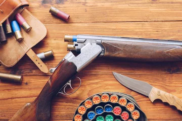 Fotobehang Jacht uitrusting. Shotgun, jachtpatronen en jachtmes op houten tafel. © SianStock