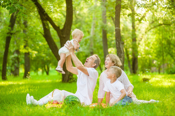 Happy family picnic. Grandfather throws up baby in the air in nature