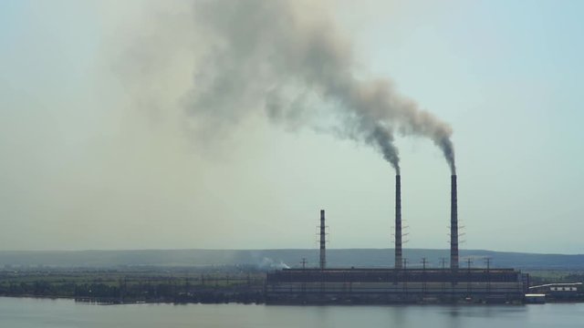 2017 year Ukraine. Burshtyn thermal power plant on the background of the reservoir. Sunny summer day Black smoke spreads around the surrounding villages and poisons them. timelipse.