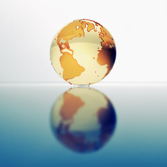 Glass globe of Earth resting on shiny surface. 3D Rendering