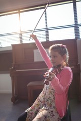 Cute girl rehearsing violin in music class