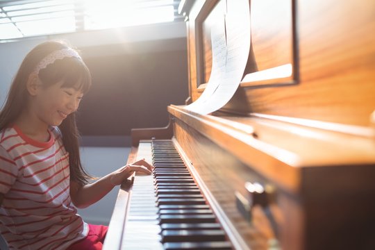 Smiling Girl Practicing Piano In Class