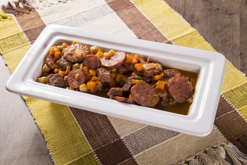 South American cuisine: Puchero soup with sausage. close-up in a pot on the table.
