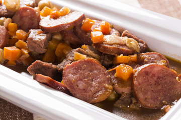 South American cuisine: Puchero soup with sausage. close-up in a pot on the table.
