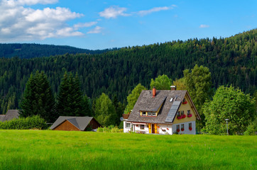 Fototapeta na wymiar Blick auf ein wunderschönes Haus unter dem blauen Himmel und Schwarzwald im Hintergrund 
