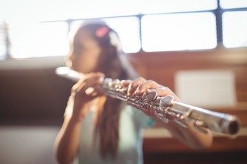 Girl practicing flute in classroom - Powered by Adobe