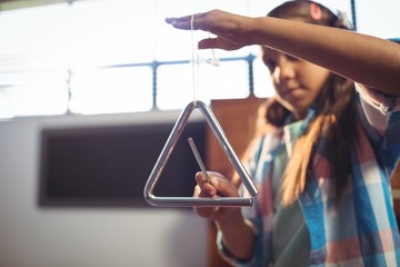 Girl playing triangle in classroom