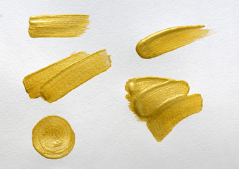 Gold paint stokes on white watercolor paper background