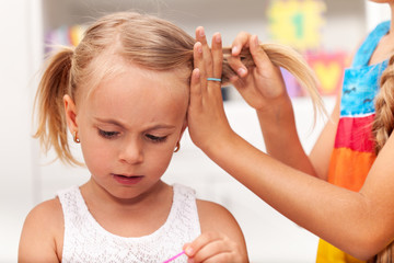 Older sister helps little girl tie her hair in plaits