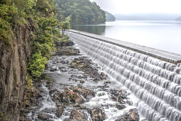 Fototapeta premium a man made spillway creates a dam along a lake next to a cliff