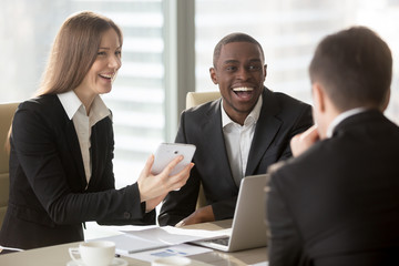 Happy smiling caucasian businesswoman using digital tablet at negotiations with multinational partners, laughing at joke on meeting. Friendly atmosphere on interview, successful teamwork in business