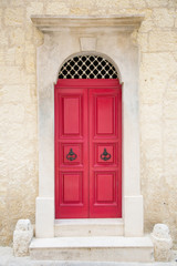 Fototapeta na wymiar Red painted old wooden door with black iron handle in medieval city street