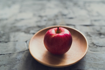 ripe red Apple wooden plate concrete background
