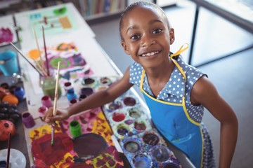 High angle portrait of elementary girl painting at desk