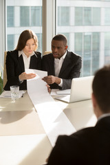 African american male and caucasian female employers reading with confusion huge resume,...